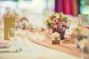 Casamento mesa contexto. lindo mesa conjunto com flores e vidro copos para alguns festivo evento, festa ou Casamento recepção foto