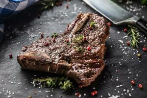 carne t-bone bife com sal Pimenta e alecrim em ardósia prato foto