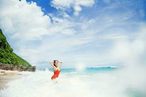 uma mulher dentro a laranja roupa de banho em pé dentro a oceano foto