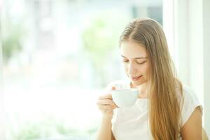 uma mulher sentado às uma mesa com uma copo do café e fruta foto