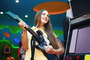 uma mulher jogando a videogames jogos com uma guitarra foto