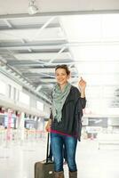 uma mulher com uma mala de viagem dentro a aeroporto foto