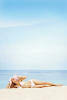 lindo mulher dentro branco bikini em de praia com chapéu foto