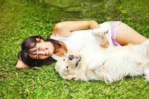 uma mulher sentado em a Relva com uma cachorro foto