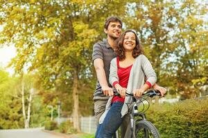 uma homem e mulher estão equitação uma bicicleta juntos foto
