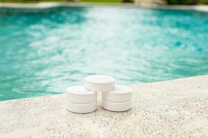 cloro comprimidos em a Beira do uma natação piscina, fechar-se do cloro comprimidos para natação piscina limpeza, cloro comprimidos para natação piscina desinfecção foto