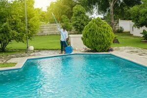 homem limpeza uma natação piscina com escumadeira, manutenção pessoa limpeza uma natação piscina com escumadeira, natação piscina limpeza e manutenção conceito. foto