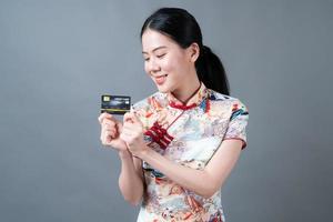 Mulher asiática usando vestido tradicional chinês com a mão segurando um cartão de crédito foto