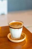 café sujo - um copo de expresso misturado com leite fresco frio foto
