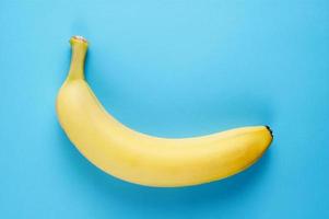 Flatlay de comida simples e saudável com uma banana fresca sobre fundo azul foto