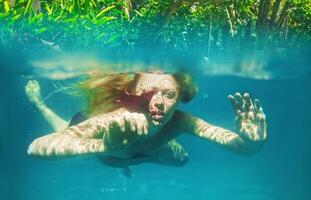 uma mulher natação embaixo da agua dentro a oceano foto