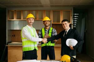 engenheiros ou arquitetura apertando as mãos no canteiro de obras para projeto arquitetônico, segurando o capacete de segurança nas mãos. cooperação bem-sucedida foto