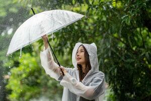 uma chuvoso dia dentro a parque. ásia mulher vestindo uma capa de chuva ao ar livre. foto