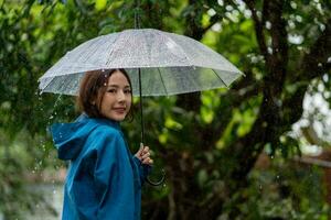 chuvoso dia ásia mulher vestindo uma capa de chuva ao ar livre. ela é feliz. foto