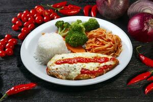 parmigiana bife com massa, arroz e legumes foto