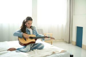 menina jogando guitarra relaxar dentro a quarto, apreciar lazer final de semana às lar. livre de estresse conceito fofa interpolação menina foto