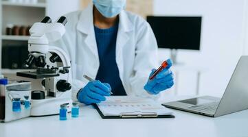 moderno médico pesquisa laboratório. africano fêmea cientista trabalhando com micro pipetas analisando bioquímico amostras, avançado Ciência químico laboratório para remédio. foto