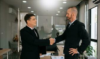 dois homens de negócios confiantes apertando as mãos durante uma reunião no escritório, sucesso, negociação, saudação e parceiro foto