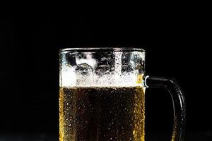 copo de cerveja com espuma de cerveja em fundo escuro foto