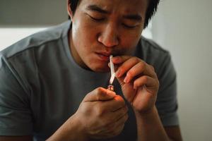 homem asiático desesperado pelo vício do fumo