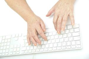 mãos do a velho fêmea digitando em a teclado, isolado em branco, fechar-se. foto