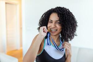 retrato do brincalhão jovem fêmea corredor sorridente a parte, de lado e morder dela ouro medalha . Esportes, ativo estilo de vida, motivação conceito foto