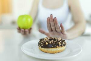 dieta ou Boa saúde conceito. jovem mulher rejeitando lixo Comida ou pouco saudável Comida tal Como rosquinha ou sobremesa e escolhendo saudável Comida tal Como fresco fruta ou vegetal. foto