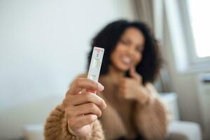 fechar-se tiro do afro-americano mulher mão segurando uma negativo teste dispositivo. feliz jovem mulher mostrando dela negativo coronavírus - covid-19 rápido teste. foco é em a test.coronavirus foto