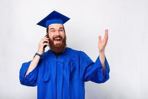 foto de um estudante espantado com uma túnica azul solteirão falando em um smartphone