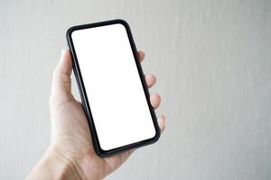 mão do homem segurando o smartphone com tela em branco em fundo cinza, close-up da mão. espaço para texto. foto