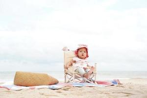 menina asiática sentada na cadeira de praia. foto