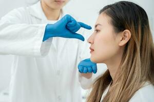 plástico cirurgia, beleza, cirurgião ou esteticista tocante mulher face, cirúrgico procedimento este envolver alterando forma do nariz, médico examina paciente nariz antes rinoplastia, médico assistência, saúde foto