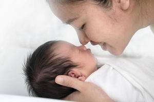 close-up jovem mãe asiática beijando seu bebê recém-nascido. o amor da mãe recém-nascido. foto