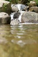 fechar-se Visão do Claro água em cascata baixa rio pedras foto