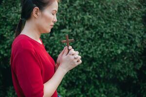 ásia mulher Rezar com madeira Cruz e acreditam dentro Deus foto