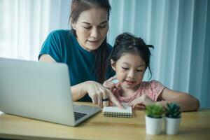 mãe feliz ajudando sua linda filha a estudar online em casa. pai e filho assistindo aula de arte juntos no laptop foto