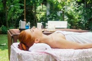 jovem lindo mulher relaxante dentro spa massagem lado de fora dentro tropical jardim. foto