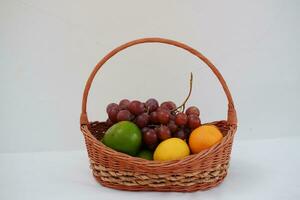 frutas dentro uma cesta em uma branco fundo. laranja, uva, limão. foto