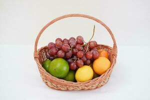 frutas dentro uma cesta em uma branco fundo. laranja, uva, limão. foto