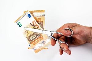 homem cortando notas de 50 euros com uma tesoura foto