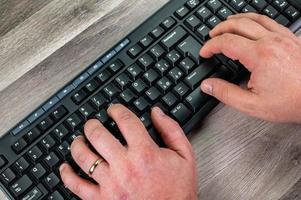 mãos de um homem digitando no teclado do pc foto