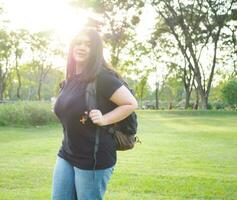 retrato jovem mulher menina ásia gordo fofa lindo grandes Preto cabelo 1 pessoa vestem Preto camisa em pé mochila preparar para viagem dentro jardim parque ao ar livre tarde luz solar fresco feliz relaxar verão foto