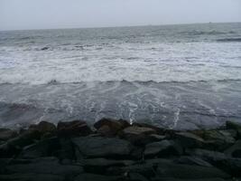 Visão do a ondas e pedras em a de praia foto