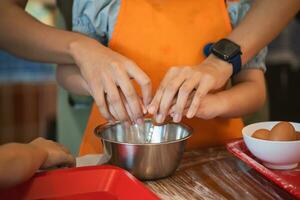 ásia menina Aprendendo para assar bolo e rachaduras ovos bolo ingredientes. cozimento Diversão. isto adorável bebê menina aprende para rachadura ovos, misturar ingredientes, e crio uma delicioso bolo com granulados e geada. foto