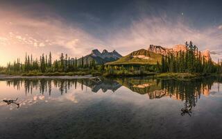 panorama do três irmãs montanha reflexão em lagoa às nascer do sol dentro outono às banff nacional parque foto