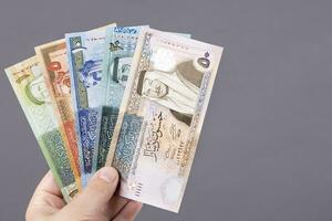 jordaniano dinar dentro a mão em uma cinzento fundo foto