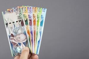 barbadiana dinheiro dentro a mão em uma cinzento fundo foto