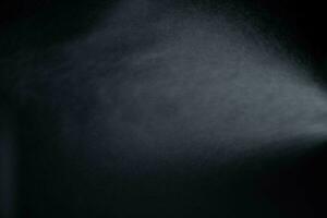 água spray poeira em Sombrio fundo. pulverização névoa efeito isolado em Preto fundo. foto