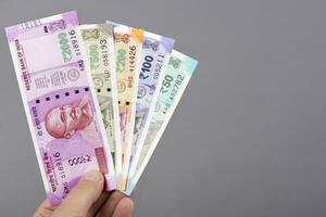 indiano dinheiro dentro a mão em uma cinzento fundo foto