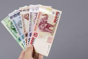 tanzaniano dinheiro dentro a mão em uma cinzento fundo foto
